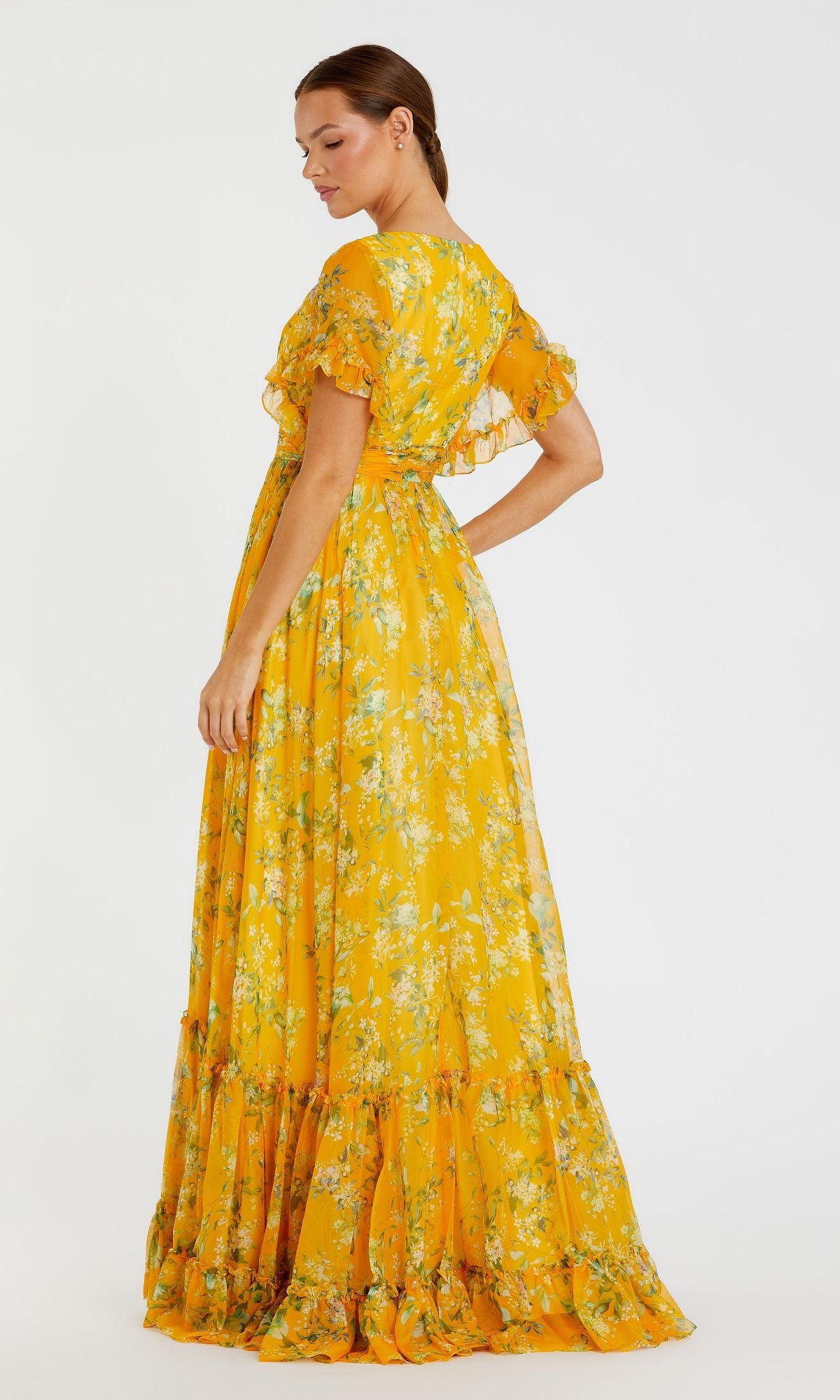 Woman in a yellow Floral-Print Long Formal Dress (70241 Mac Duggal) with Bohemian style, ruffled sleeves, and hem, standing sideways against a plain white background.